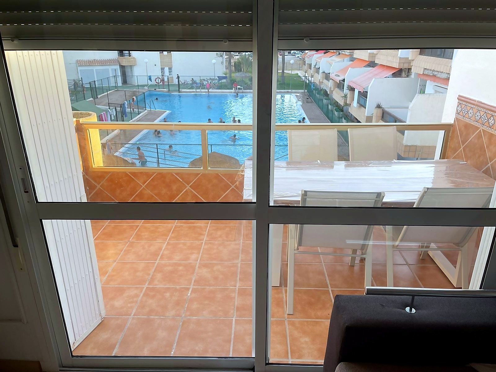 Terraza con mesa y vistas a la piscina comunitaria
